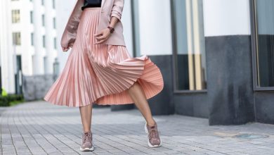 Pleated skirt coral color and sneakers. The girl is very dynamic posing on the street, the skirt is developing.